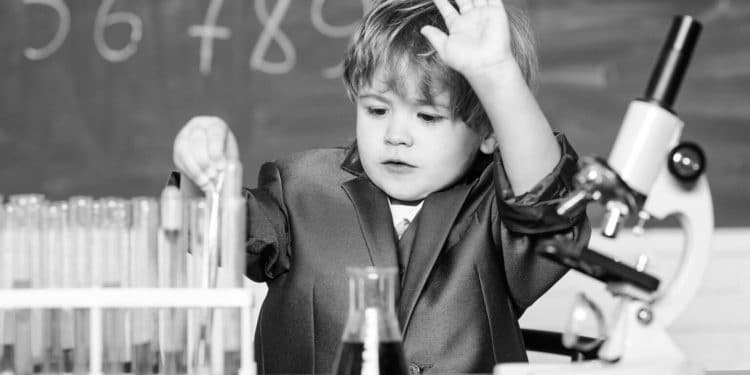 Technology and science concept. Kid study biology and chemistry in school. School education. Explore biological molecules. Toddler genius baby. Boy near microscope and test tubes in school classroom
