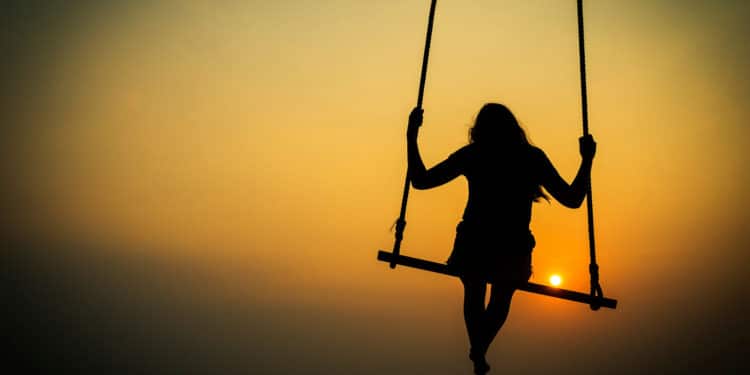 Teenager girl on a swing silhouette on a background of sunset sky and sea. Thailand, Southeast Asia